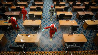 Petugas menyemprotkan cairan disinfektan di ruang sidang paripurna DPRD DKI Jakarta, Rabu (29/7/2020). [ANTARA FOTO/Rivan Awal Lingga]