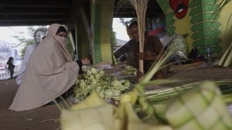 Pedagang kulit ketupat melayani pembeli di bawah jalan tol di kawasan Bintaro, Jakarta, Kamis (30/7/2020). [Suara.com/Angga Budhiyanto]