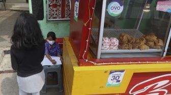 Siswi kelas 2 SDN 01 Pagi Bukit Duri Keysha Nayara Effeni (8) belajar secara online di gerai makanan tempat Ibunya berjualan di kawasan Bukit Duri, Jakarta, Kamis (30/7/2020). [Suara.com/Angga Budhiyanto]