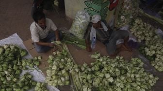 Pedagang menyelesaikan pembuatan kulit ketupat di bawah jalan tol di kawasan Bintaro, Jakarta, Kamis (30/7/2020). [Suara.com/Angga Budhiyanto]