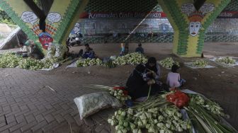 Pedagang menyelesaikan pembuatan kulit ketupat di bawah jalan tol di kawasan Bintaro, Jakarta, Kamis (30/7/2020). [Suara.com/Angga Budhiyanto]