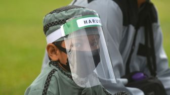 Seorang anak menggunakan alat pelindung wajah saat mengikuti salat Idul Adha berjamaah di Lapangan Vatulemo, Palu, Sulawesi Tengah, Jumat (31/7/2020). [Foto/Antara]