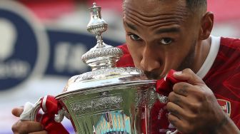 Striker Arsenal Pierre-Emerick Aubameyang mencium piala saat merayakan kemenangan dengan tim setelah memenangkan pertandingan final Piala FA Inggris antara Arsenal melawan Chelsea  di  Wembley Stadion, London, Sabtu (1/8/2020). [Adam Davy / POOL / AFP]