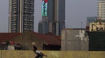 Seorang anak bermain sepakbola di rooftop Pasar Jaya Mampang, Jakarta, Minggu (2/8/2020). [Suara.com/Angga Budhiyanto]