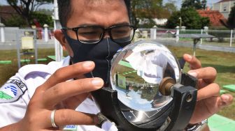 Petugas Badan Meteorologi, Klimatologi dan Geofisika (BMKG) memeriksa alat pengukur intensitas dan durasi penyinaran matahari (Campbell Stokes) di Laboratorium BMKG Serang, Banten, Senin (3/8/2020).  [ANTARA FOTO/Asep Fathulrahman]