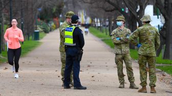 Petugas kepolisian berbincang bersama tentara saat melakukan patroli di Melbourne, Australia, Selasa (4/8).  [AFP/William WEST]