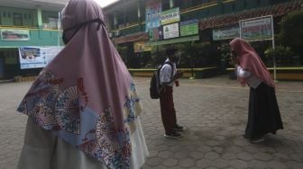 Siswa menyalami guru sebelum memasuki ruang kelas di SDN Pekayon Jaya VI, Kota Bekasi, Jawa Barat, Selasa (4/8/2020). [Suara.com/Angga Budhiyanto]