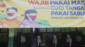 Sejumlah siswa mengantre sebelum memasuki ruang kelas di SDN Pekayon Jaya VI, Kota Bekasi, Jawa Barat, Selasa (4/8/2020). [Suara.com/Angga Budhiyanto]