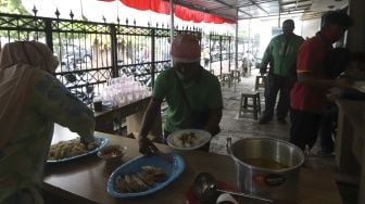 Petugas melayani warga yang hendak menyantap hidangan makan gratis di Jalan Jenderal Basuki Rachmat, Cipinang Besar Selatan, Jakarta, Rabu (5/8/2020). [Suara.com/Angga Budhiyanto]