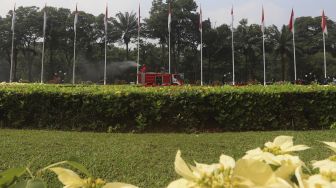 Petugas pemadam kebakaran menyemprotkan cairan disinfektan di area komplek Gedung DPR/MPR RI, Jakarta, Minggu (9/8/2020). [Suara.com/Angga Budhiyanto]