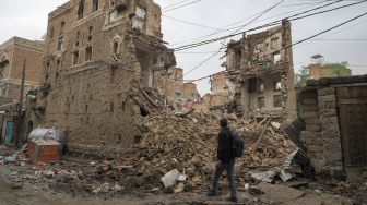 Seorang pria berjalan melewati bangunan bersejarah di Kota Tua Sanaa, Yaman, pada (8/8/2020). [Mohammed HUWAIS / AFP]