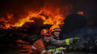 Petugas pemadam kebakaran berusaha memadamkan api yang membakar salah satu gudang pabrik kapas di Cipadung, Bandung, Jawa Barat, Selasa (11/8/2020).  [ANTARA FOTO/Raisan Al Faris]