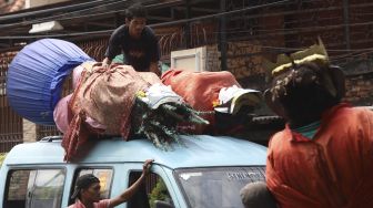 Warga menaikkan ondel-ondel ke atas mobil angkutan umum di Kampung Ondel-ondel, Jalan Kembang Pacar, Senen, Jakarta, Rabu (12/8/2020). [Suara.com/Angga Budhiyanto]