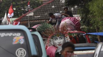 Warga menaikkan ondel-ondel ke atas mobil angkutan umum di Kampung Ondel-ondel, Jalan Kembang Pacar, Senen, Jakarta, Rabu (12/8/2020). [Suara.com/Angga Budhiyanto]