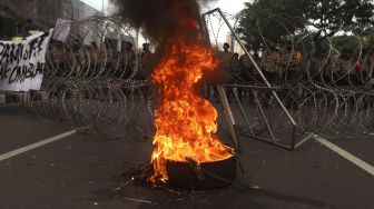 Massa mahasiswa dari berbagai universitas membakar ban saat melakukan aksi unjuk rasa di sekitar Gedung DPR/MPR RI, Jumat (14/8/2020). [Suara.com/Angga Budhiyanto]