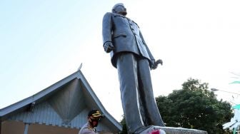 Kapolres Blitar Kota AKBP Leonard M. Sinambela membersihkan patung presiden Soekarno di Muesum Istana Gebang Blitar, Jawa Timur, Sabtu (15/8/2020). [ANTARA FOTO/Irfan Anshori]