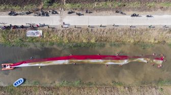 Foto udara kain Merah Putih dibentangkan oleh komunitas Pasukan Susur Sungai dan Ekosistem Rancaekek (Passer) di sungai Cikijing, Rancaekek, Kabupaten Bandung, Jawa Barat, Minggu (16/8/2020). [ANTARA FOTO/M Agung Rajasa]