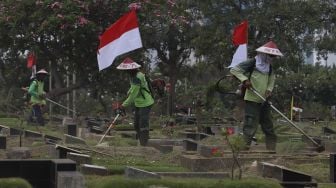 Petugas Pertamanan dan Kehutanan Kota Jakarta Pusat mengenakan atribut kemerdekaan saat memangkas rumput di TPU Karet Bivak, Tanah Abang, Jakarta Pusat, Minggu (16/8/2020). [Suara.com/Angga Budhiyanto]