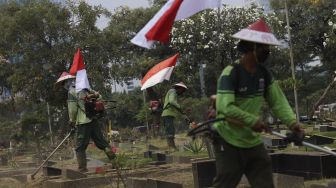 Petugas Pertamanan dan Kehutanan Kota Jakarta Pusat mengenakan atribut kemerdekaan saat memangkas rumput di TPU Karet Bivak, Tanah Abang, Jakarta Pusat, Minggu (16/8/2020). [Suara.com/Angga Budhiyanto]