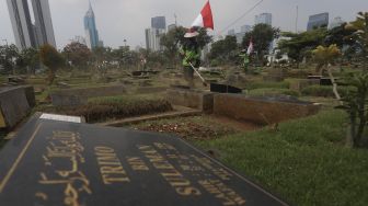 Petugas Pertamanan dan Kehutanan Kota Jakarta Pusat mengenakan atribut kemerdekaan saat memangkas rumput di TPU Karet Bivak, Tanah Abang, Jakarta Pusat, Minggu (16/8/2020). [Suara.com/Angga Budhiyanto]