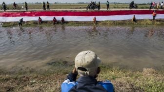 Komunitas Pasukan Susur Sungai dan Ekosistem Rancaekek (Passer) membentangkan kain Merah Putih di bantaran sungai Cikijing, Rancaekek, Kabupaten Bandung, Jawa Barat, Minggu (16/8/2020). [ANTARA FOTO/M Agung Rajasa]