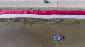 Foto udara kain Merah Putih dibentangkan oleh komunitas Pasukan Susur Sungai dan Ekosistem Rancaekek (Passer) di sungai Cikijing, Rancaekek, Kabupaten Bandung, Jawa Barat, Minggu (16/8/2020). [ANTARA FOTO/M Agung Rajasa]