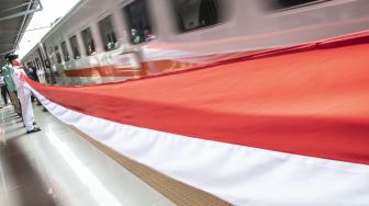 Paskibraka membentangkan bendera Merah Putih di samping rangkaian KA Serayu di Peron 1 Stasiun Pasar Senen, Jakarta, Senin (17/8/2020).  [ANTARA FOTO/Aprillio Akbar]