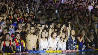 Foto yang diambil pada tanggal 15 Agustus 2020 menunjukkan orang-orang menonton pertunjukan saat mereka mendinginkan diri di sebuah kolam renang di Wuhan, Provinsi Hubei, China. [STR / AFP]