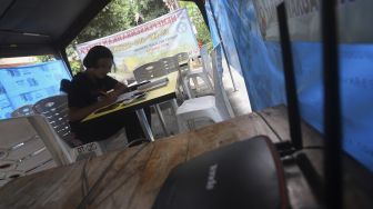 Siswa belajar secara online di tenda wifi gratis di taman warga RT 013, Pondok Kelapa, Jakarta Timur, Selasa (18/8/2020). [Suara.com/Angga Budhiyanto]