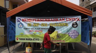 Seorang siswa melintas di depan tenda wifi gratis di taman warga RT 013, Pondok Kelapa, Jakarta Timur, Selasa (18/8/2020). [Suara.com/Angga Budhiyanto]