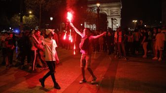 Suporter Paris Saint-Germain (PSG) menyalakan kembang api saat merayakan kemenangan 3-0 tim mereka atas RB Leipzig yang membuat PSG lolos ke final Liga Champions di Champs-Elysees Avenue dekat Arc de Triomphe, Paris, Perancis, Rabu (19/8) dini hari WIB.  [GEOFFROY VAN DER HASSELT / AFP]