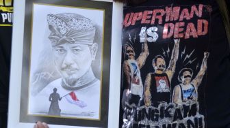 Warga membawa sketsa wajah drummer Superman is Dead I Gede Ari Astina alias Jerinx sebagai bentuk dukungan saat Jerinx menjalani pemeriksaan di Polda Bali, Denpasar, Bali, Selasa (18/8/2020). [ANTARA FOTO/Fikri Yusuf]