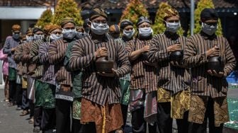 Pasukan Patangpuluh Kendi Kasepuhan Girikusumo dengan mengenakan masker mengirab kendi berisi air dari sumur berkah Girikusumo sebagai simbol berkah alam dalam prosesi Tradisi Kirab Sura Girikusumo di Desa Banyumeneng, Mranggen, Demak, Jawa Tengah, Kamis (20/8/2020). [ANTARA FOTO/Aji Styawan]