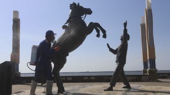 Seorang petugas menyemprotkan cairan disinfektan di kawasan pantai Ancol, Jakarta Utara, Jumat (21/8/2020). [Suara.com/Angga Budhiyanto]