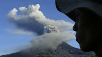 Warga mengamati Gunung Sinabung yang menyemburkan material vulkanik saat erupsi di Desa Tiga Pancur, Karo, Sumatera Utara, Minggu (23/8/2020). [ANTARAFOTO/Edy Regar]
