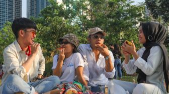 Warga piknik di area Hutan Kota Gelora Bung Karno, Senayan, Jakarta Sekatan, Minggu (23/8). [Suara.com/Alfian Winanto]