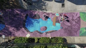 Foto udara sejumlah pelukis dari Komunitas Perupa Jakarta melukis mural 3D di sepanjang Jalan Keuangan Raya, Cilandak Barat, Jakarta Selatan, Selasa (25/8/2020). [Suara.com/Angga Budhiyanto]