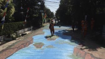 Petugas PPSU membersihkan area jalan yang dihiasi mural 3D di sepanjang Jalan Keuangan Raya, Cilandak Barat, Jakarta Selatan, Selasa (25/8/2020). [Suara.com/Angga Budhiyanto]