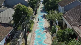 Foto udara petugas PPSU membersihkan area jalan yang dihiasi mural 3D di sepanjang Jalan Keuangan Raya, Cilandak Barat, Jakarta Selatan, Selasa (25/8/2020). [Suara.com/Angga Budhiyanto]