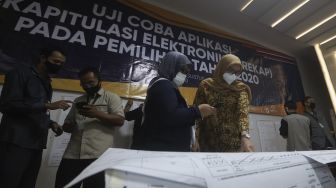 Komisioner KPU Evi Novida Ginting Manik (kanan) didampingi petugas KPU melakukan uji coba penghitungan data suara menggunakan aplikasi rekapitulasi elektronik (Sirekap) di Gedung Komisi Pemilihan Umum Republik Indonesia, Jakarta, Selasa (25/8/2020). [Suara.com/Angga Budhiyanto]