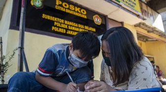 Orang tua siswa membimbing anaknya belajar daring memanfaatkan jaringan internet gratis di kolong rel kereta api Mangga Besar, Jakarta, Rabu (26/8/2020).  [ANTARA FOTO/Nova Wahyudi]