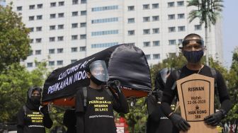 Aktivis buruh yang tergabung dalam Serikat Buruh Migran Indonesia (SBMI) dan Greenpeace Indonesia melakukan aksi damai di depan Istana Merdeka, Jakarta, Kamis (27/8/2020). [Suara.com/Angga Budhiyanto]