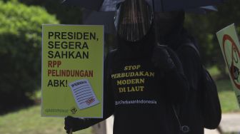 Aktivis buruh yang tergabung dalam Serikat Buruh Migran Indonesia (SBMI) dan Greenpeace Indonesia membawa poster saat melakukan aksi damai di depan Istana Merdeka, Jakarta, Kamis (27/8/2020). [Suara.com/Angga Budhiyanto]