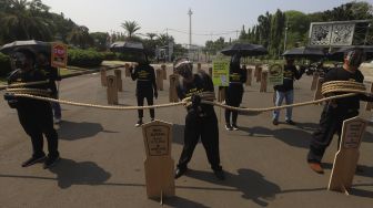 Aktivis buruh yang tergabung dalam Serikat Buruh Migran Indonesia (SBMI) dan Greenpeace Indonesia melakukan aksi damai di depan Istana Merdeka, Jakarta, Kamis (27/8/2020). [Suara.com/Angga Budhiyanto]