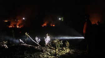 Petugas BPBD Kota Pekanbaru berusaha memadamkan api ketika terjadi kebakaran lahan di Pekanbaru, Riau, Kamis (27/8/2020) malam. [ANTARA FOTO/Rony Muharrman]