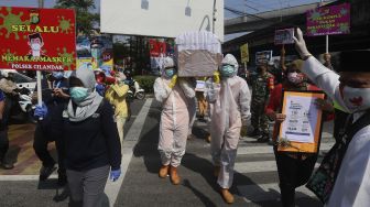 Petugas gabungan dari Kecamatan Cilandak dan Polsek Cilandak melakukan aksi sosialisasi bahaya COVID-19 dengan mengarak instalasi peti mati jenazah di kawasan Fatmawati, Jakarta, Jumat (28/8/2020). [Suara.com/Angga Budhiyanto]