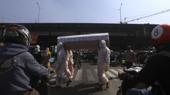 Petugas gabungan dari Kecamatan Cilandak dan Polsek Cilandak melakukan aksi sosialisasi bahaya COVID-19 dengan mengarak instalasi peti mati jenazah di kawasan Fatmawati, Jakarta, Jumat (28/8/2020). [Suara.com/Angga Budhiyanto]