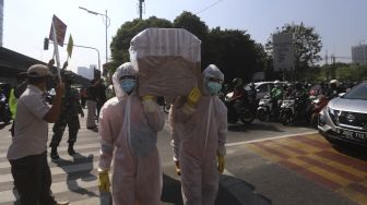 Petugas gabungan dari Kecamatan Cilandak dan Polsek Cilandak melakukan aksi sosialisasi bahaya COVID-19 dengan mengarak instalasi peti mati jenazah di kawasan Fatmawati, Jakarta, Jumat (28/8/2020). [Suara.com/Angga Budhiyanto]