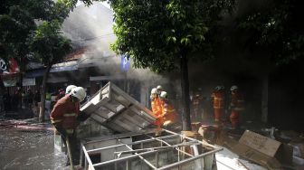 Petugas Dinas Pemadam Kebakaran memadamkan toko elektronik yang terbakar di Jalan Kranggan, Surabaya, Jawa Timur, Minggu (30/8/2020). [ANTARA FOTO/Didik Suhartono]
