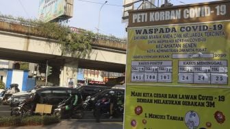 Sejumlah kendaraan melintas di samping replika peti mati korban COVID-19 di Simpang Lima Senen, Jakarta, Selasa (1/9/2020). [Suara.com/Angga Budhiyanto]